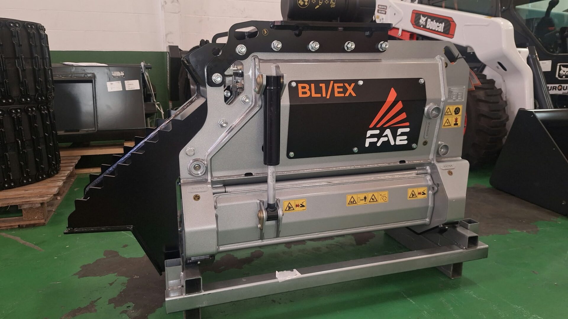 Cabezal triturador forestal FAE BL1/EX para excavadora en las instalaciones de Talleres Turquino, con una cargadora Bobcat al fondo.